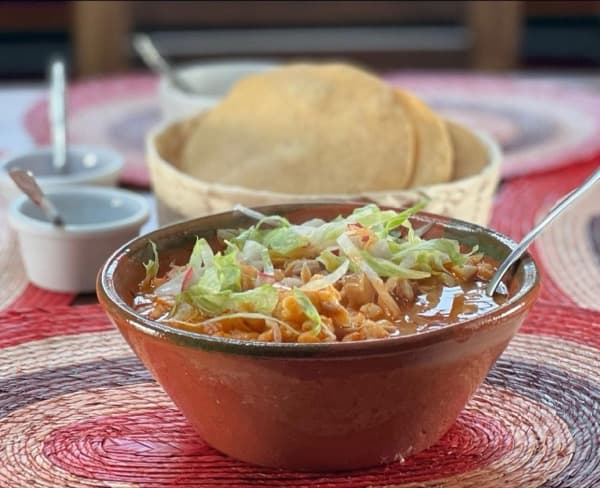 Pozole servido con tostadas